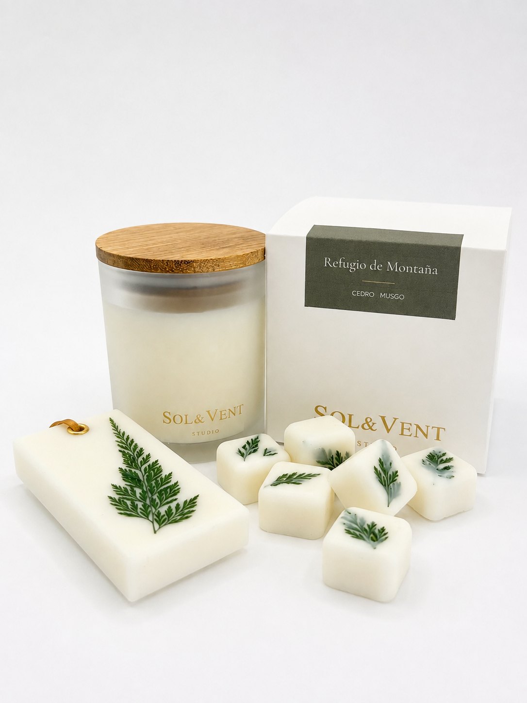 Wax melts Sol&Vent con hojas de helecho junto a la vela y la caja de Refugio de Montaña