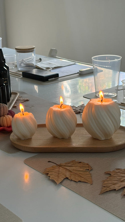 Velas con forma de calabaza encendidas sobre una bandeja de madera en el taller de otoño de Sol&Vent